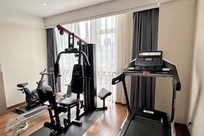 A home gym with a treadmill, elliptical, and weight machine. - Hongbang Hotel (Hangzhou)