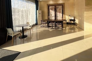 A hotel room with a dining area, a bed, and a large window with curtains. - Hongbang Hotel (Hangzhou)