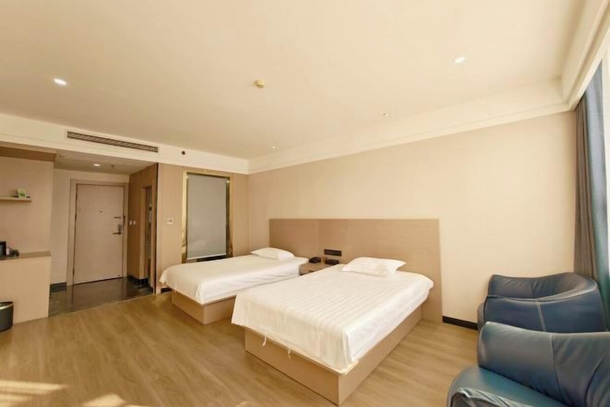 A hotel room with two beds, a seating area, and a bathroom.