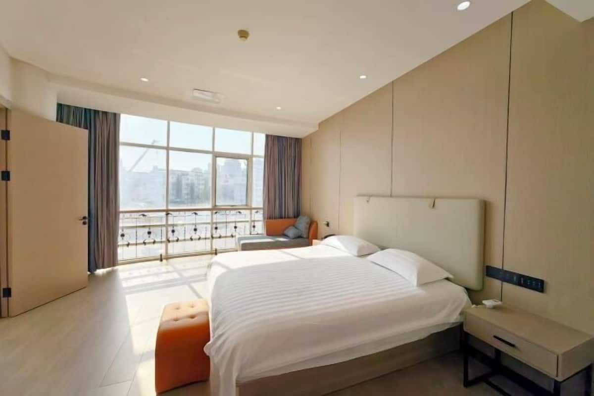 Ein modernes Hotelzimmer mit einem großen Bett, einem Nachttisch, einem Fenster mit Blick und einem Balkon.