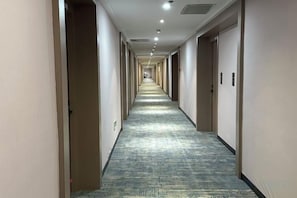 A long, narrow hotel corridor with doors on both sides, carpeted flooring, and recessed lighting on the ceiling. - Hongbang Hotel (Hangzhou)