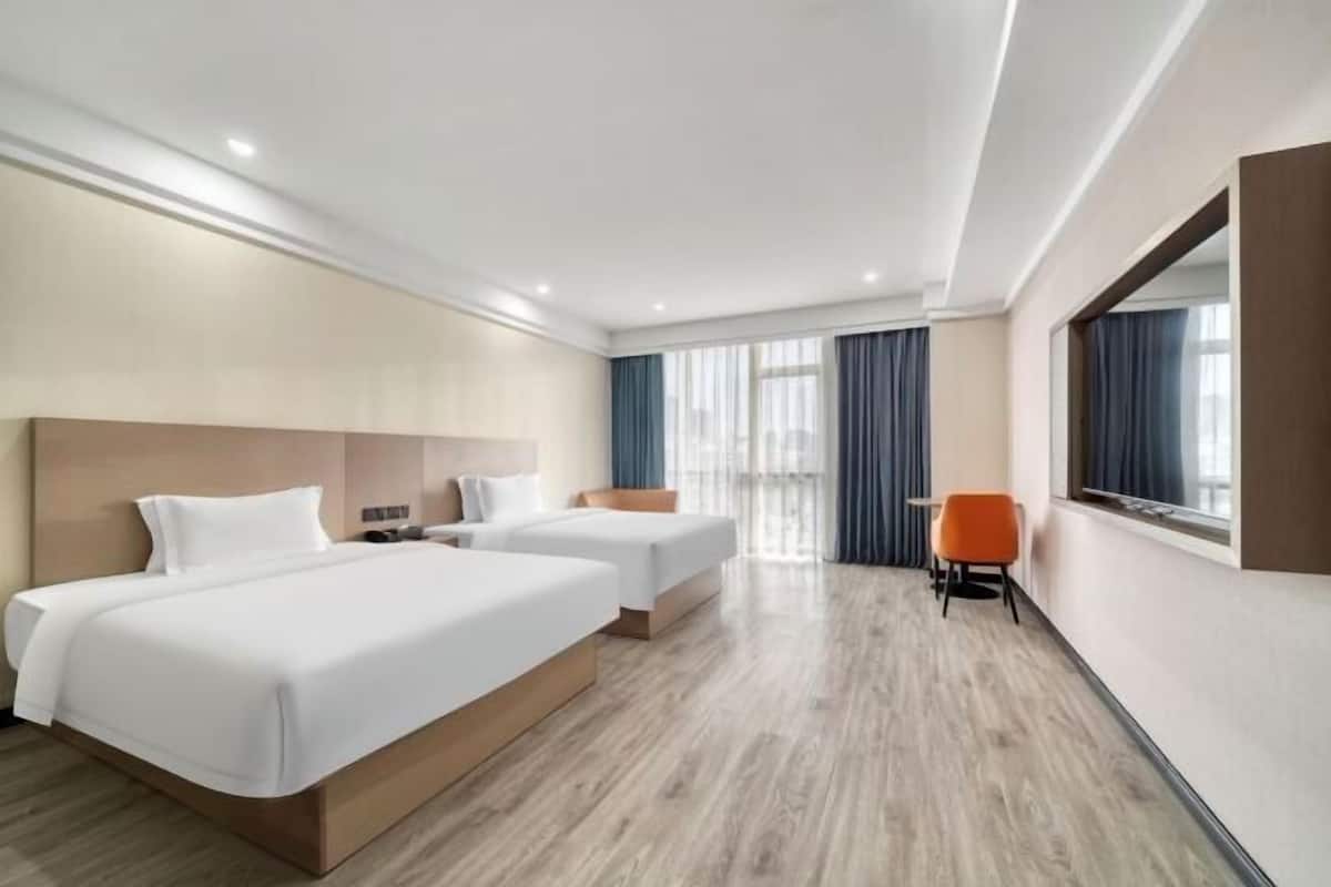 Ein Hotelzimmer mit zwei Betten, einer Sitzecke und einem großen Fenster.