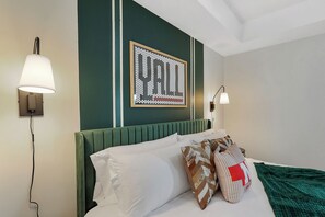 A hotel room with a green headboard, white bedding, and a framed artwork on the wall. - Spacious 5BD - UNL 5mins - BBQ, Games & Backyard (Lincoln)