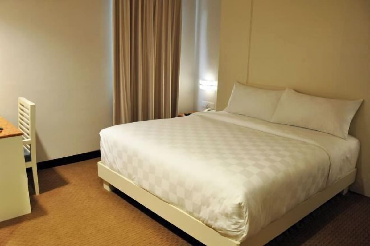Ein Hotelzimmer mit Bett, Schreibtisch und einem fenster mit Vorhängen.