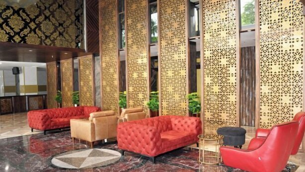 Eine Lobby mit roten und beigen Sofas, einem Marmorboden und dekorativen Wandverkleidungen.