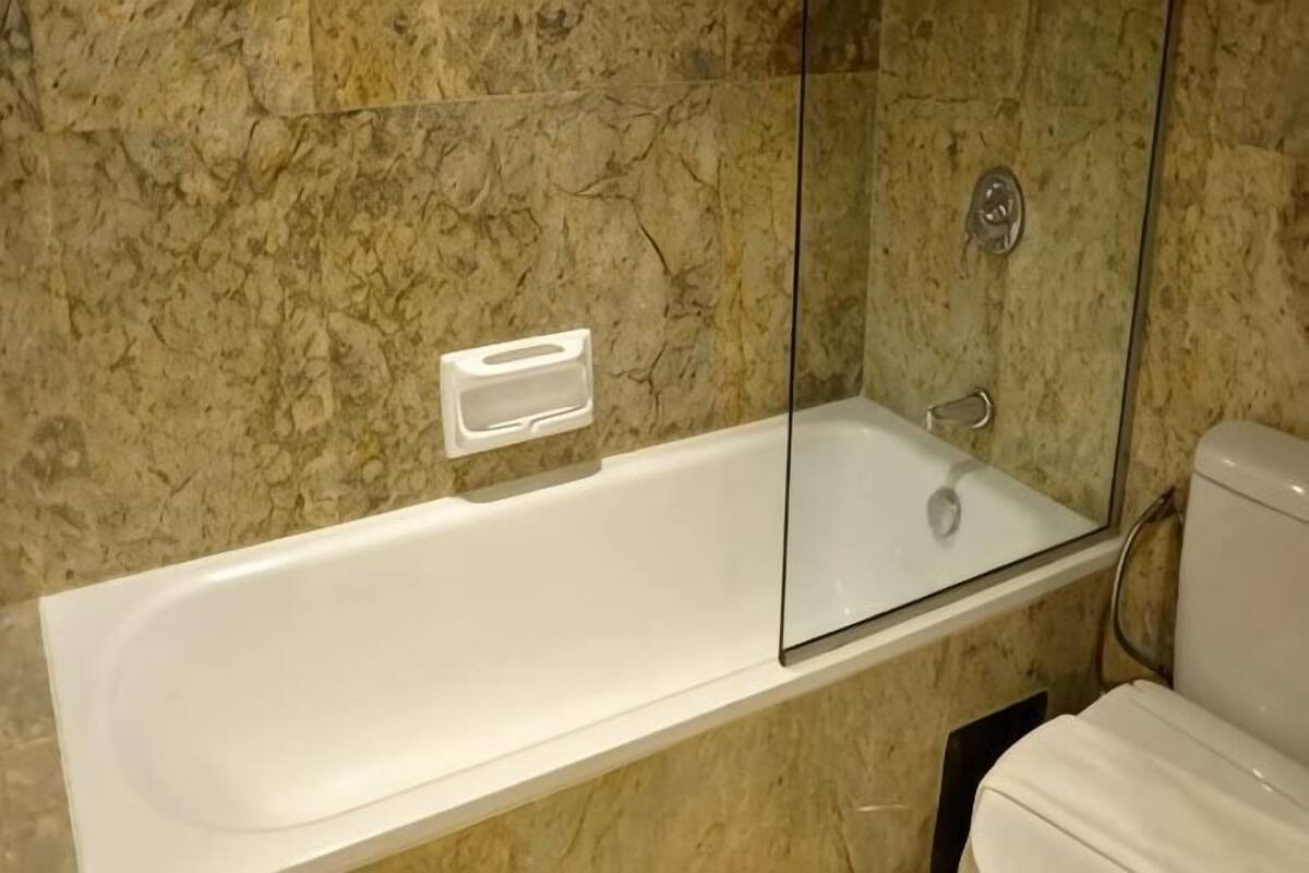 Une salle de bain avec une baignoire, des toilettes et un mur en marbre.