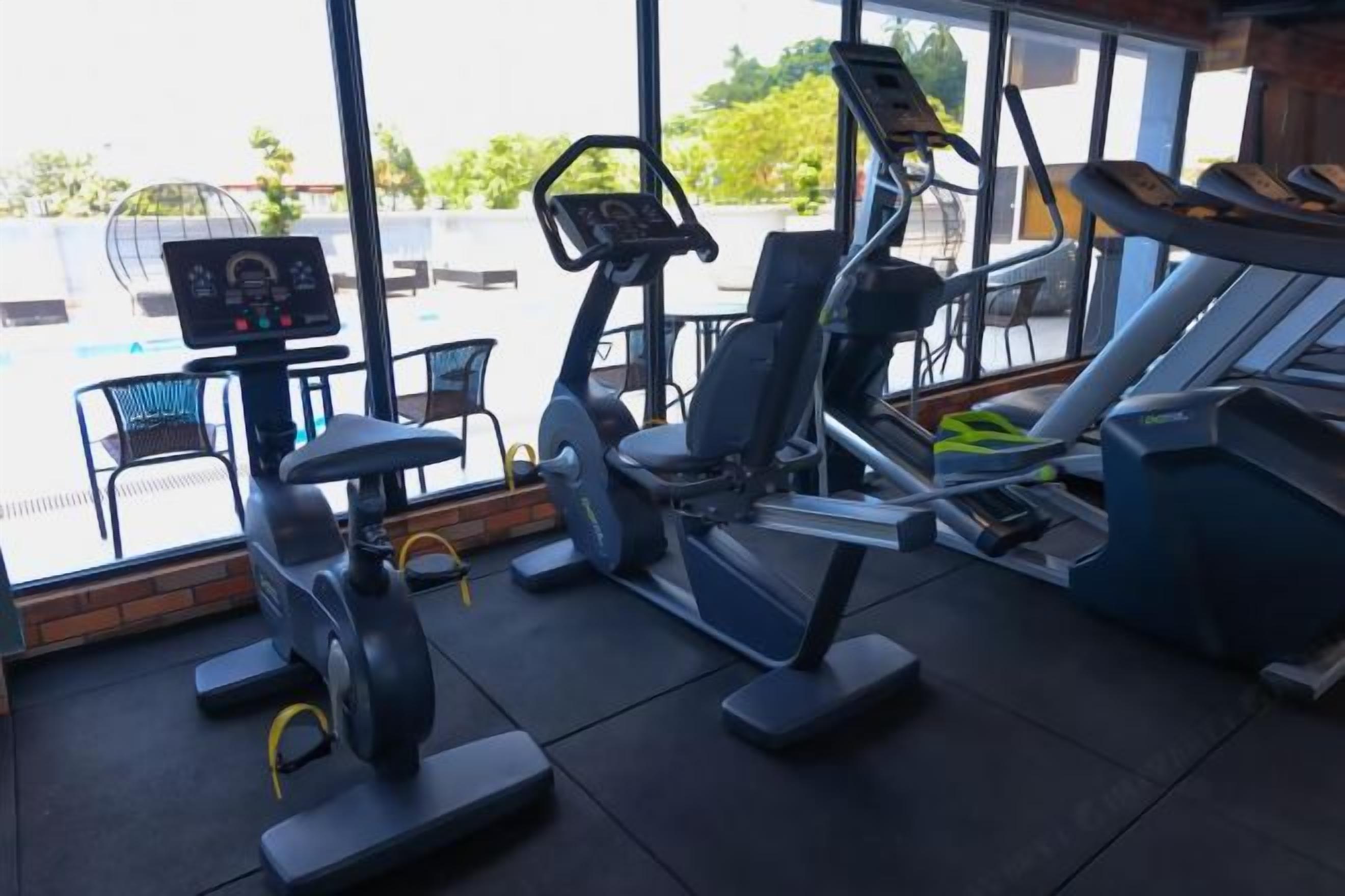 A gym with cardio machines, weight benches, and a control panel.
