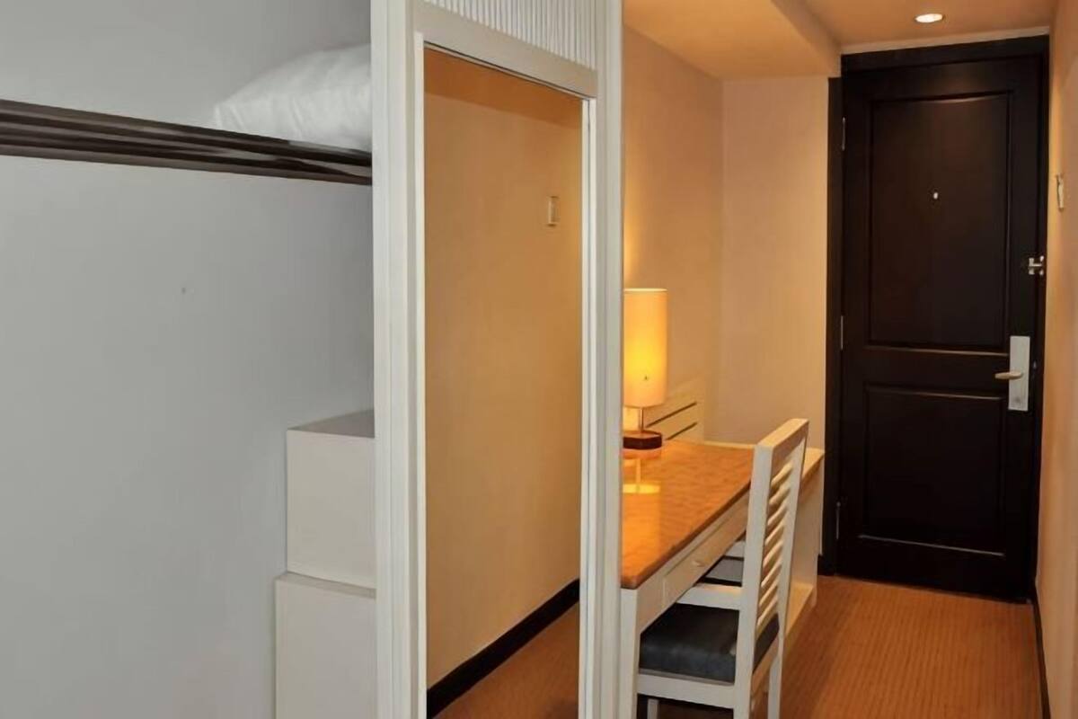 Une petite pièce comprenant un lit, un bureau et une porte.