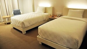 Ein Hotelzimmer mit zwei Betten, einem Sessel, einem kleinen Tisch und einer Lampe.