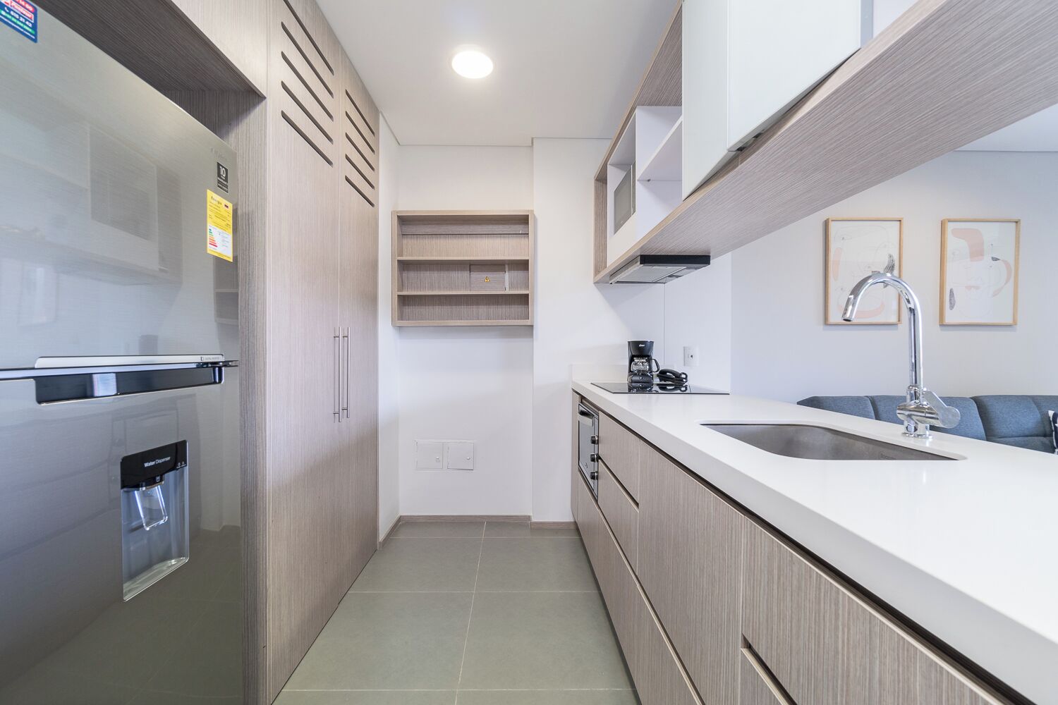 Una cocina moderna con refrigerador integrado, dispensador de agua, cafetera y pileta.