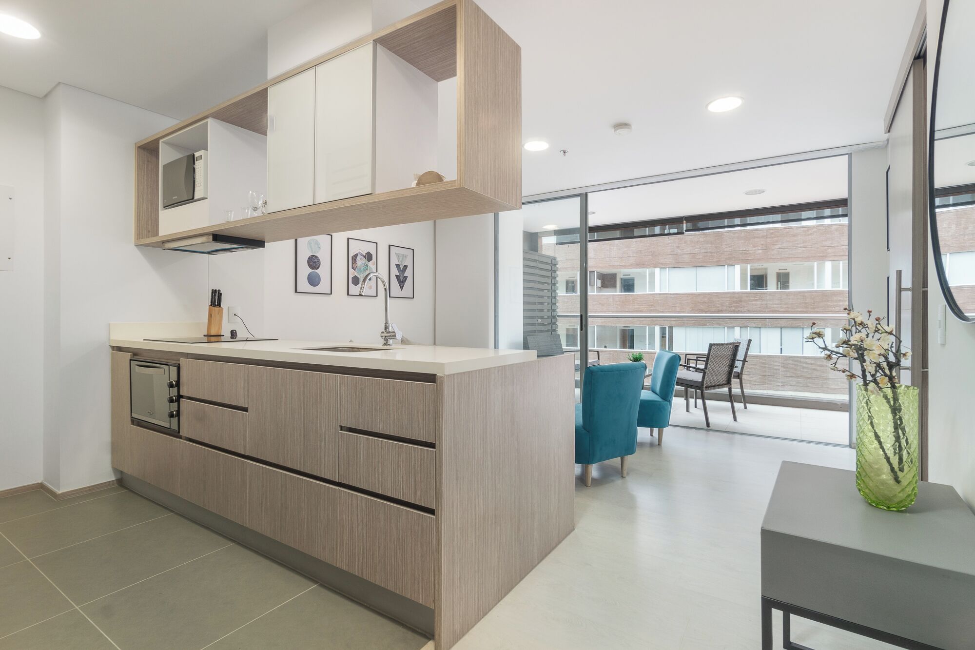 A modern kitchen with a built-in oven, a sink, and a dining area with a table and chairs.