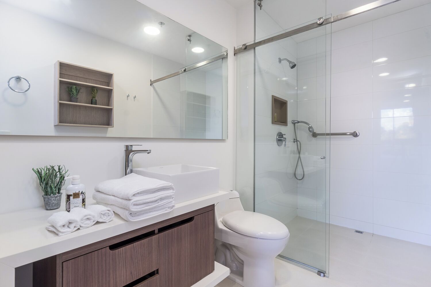 Une salle de bain moderne avec une douche à parois de verre, un lavabo blanc et un meuble-lavabo avec un miroir.