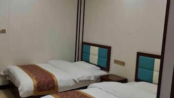 A hotel room with two beds, each with a wooden headboard and a nightstand.