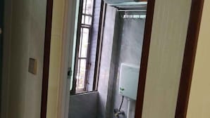 A narrow hallway with a window, a blue bucket, and a water heater. - Enshi Xueyuan Hotel (Enshi City)