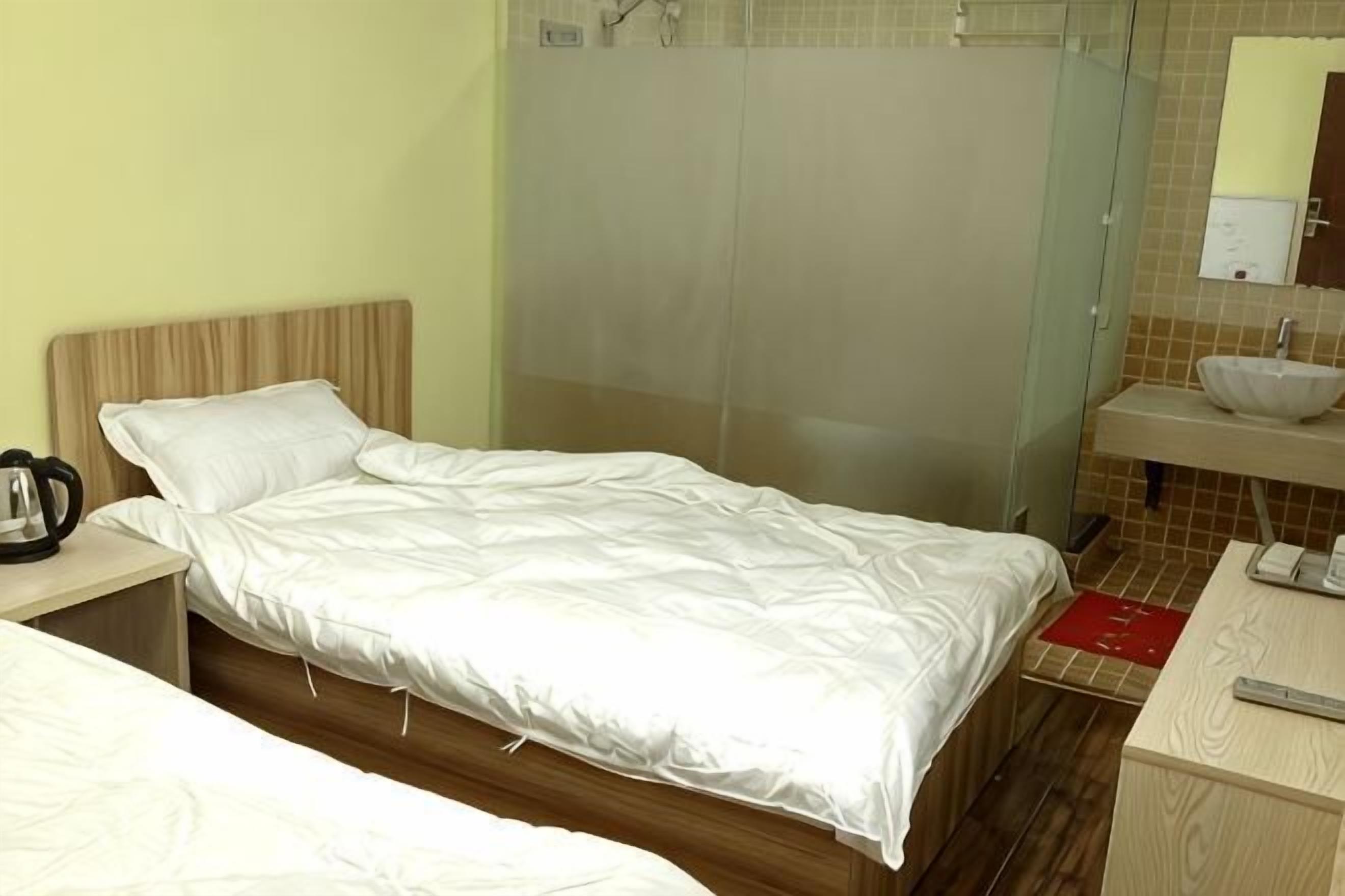 A hotel room with a bed, bedside table, and a bathroom with a sink and mirror.