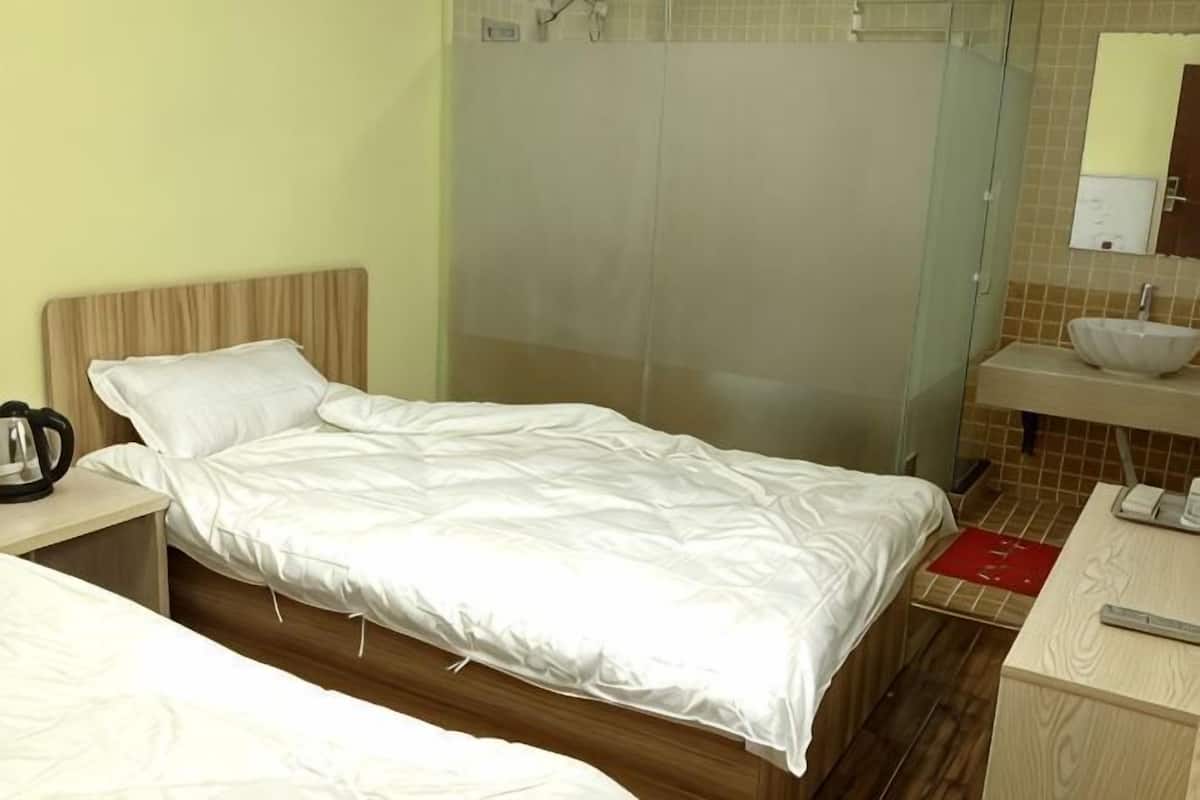 Een hotelkamer met een bed, nachtkastje en een badkamer met wastafel en spiegel.