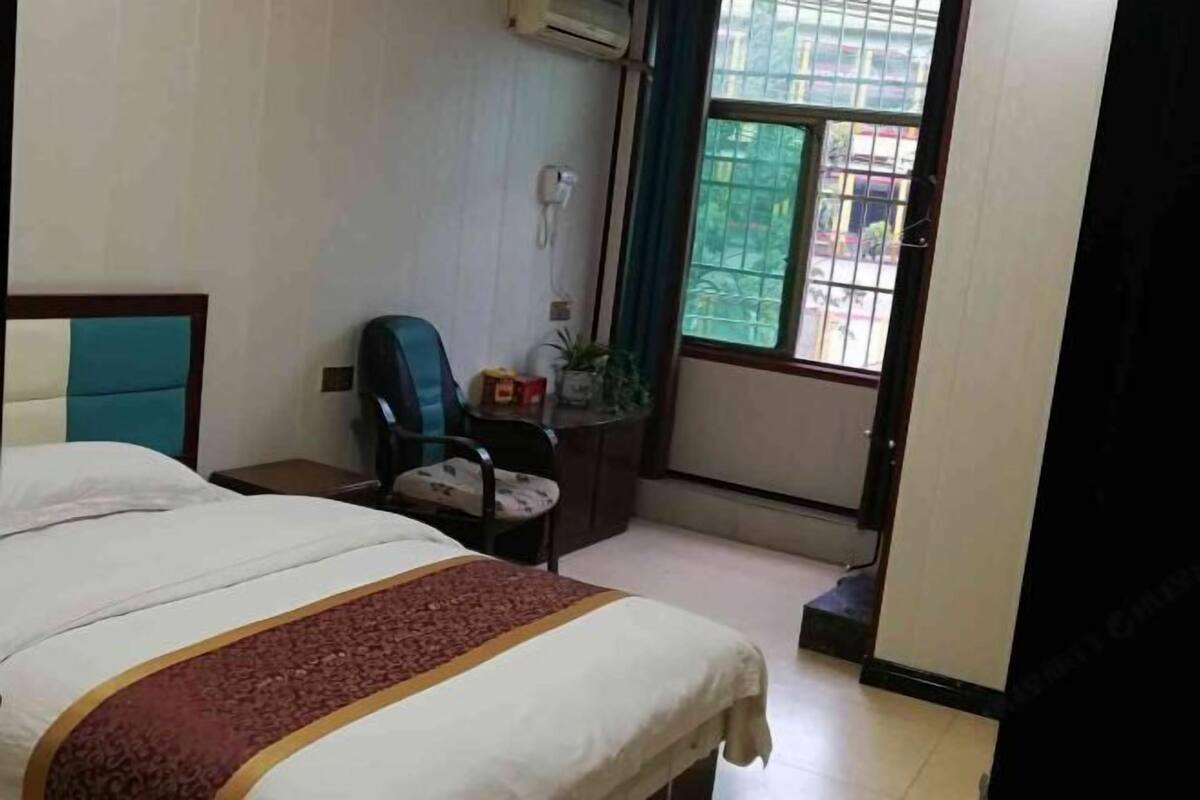 Een hotelkamer met een bed, een bureau, een stoel, een kamerplant en een raam met uitzicht.
