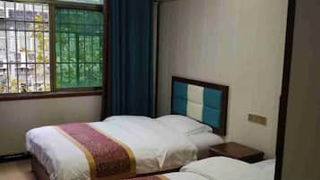 A hotel room with two beds, a window with bars, and an air conditioning unit.