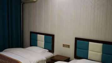 A hotel room with two beds, a nightstand, and a wall-mounted air conditioner.