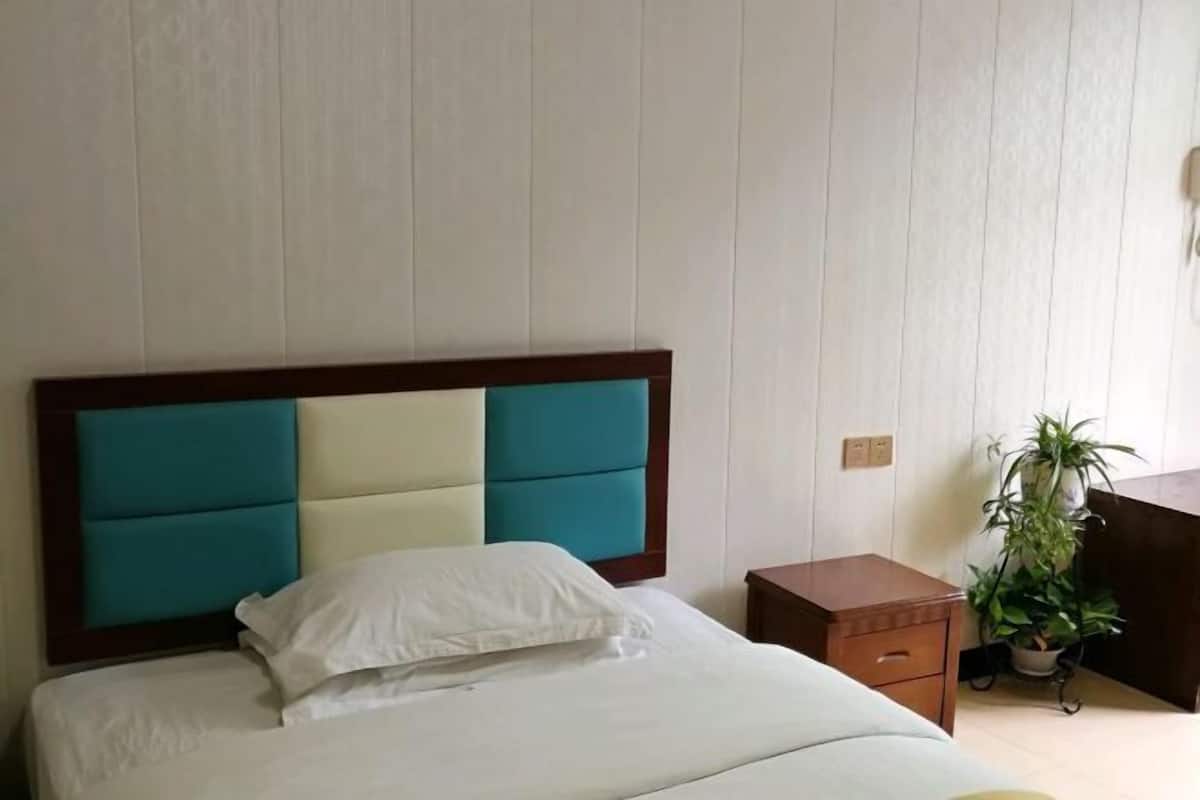 Een hotelkamer met een bed, nachtkastje en een potplant.