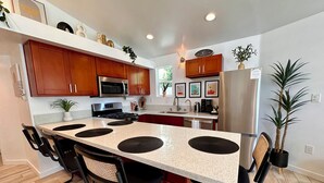 Una cocina moderna con armarios de madera, electrodomésticos de acero inoxidable y una isla central con tapetes negros.