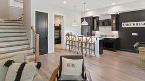 A modern kitchen with a bar area, a dining set, and a staircase leading to another level. - Lakeside Bliss w/Dock, Kayaks, Fire Pit, Foosball (Estill Springs)