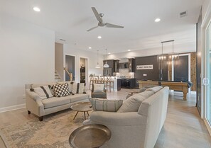 A modern living room with a sofa, armchairs, a coffee table, and a dining area with a table and chairs. - Lakeside Bliss w/Dock, Kayaks, Fire Pit, Foosball (Estill Springs)