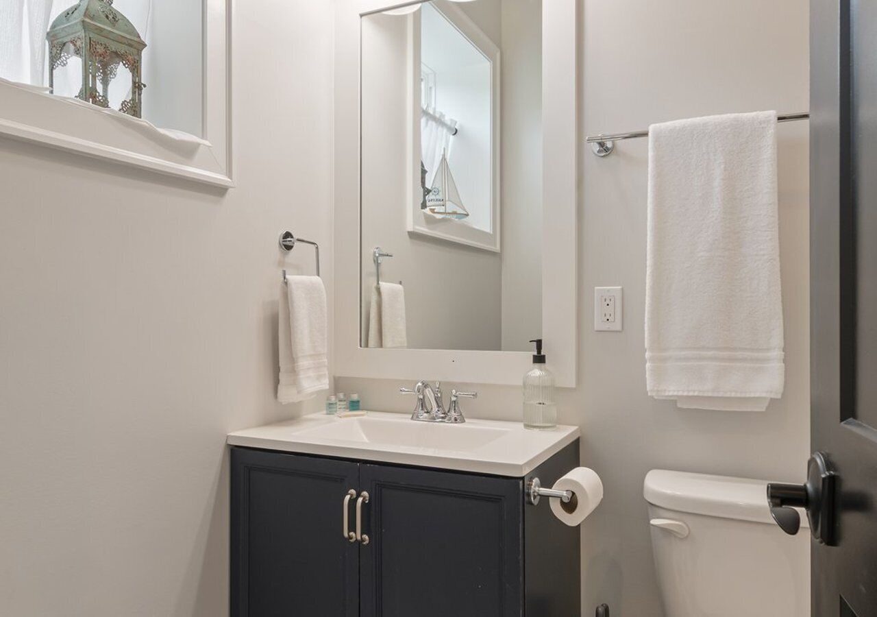 A bathroom with a sink, mirror, towel rack, and toilet.