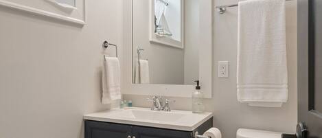 A bathroom with a sink, mirror, towel rack, and toilet.
