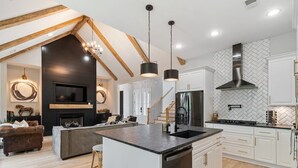 A modern kitchen with a central island, white cabinetry, and a herringbone-patterned backsplash. - Lakeside Bliss w/Dock, Kayaks, Fire Pit, Foosball (Estill Springs)