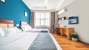 Habitación de hotel con dos camas, un escritorio, una silla, un televisor y una ventana con cortinas.