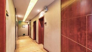 Un pasillo de hotel con suelo de madera, puertas de madera y pared de color claro.