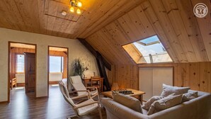 Une pièce confortable de style loft, avec des poutres en bois, une lucarne, un canapé, un fauteuil et une table d’échecs.