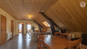 Une pièce mansardée spacieuse, avec un plancher en bois, une table à manger et un canapé.