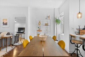 Ein stilvoller Essbereich mit Holztisch, gelben Stühlen und einer weißen Regaleinrichtung mit Dekorationselementen.