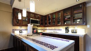 A kitchen with wooden cabinets, a microwave, and a coffee maker. - A-505 Enjoy Your Vacation In This Charming Condominium! (Cabo San Lucas)