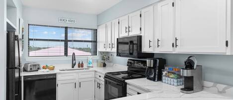 A modern kitchen with white cabinets, a black stove, and a microwave.