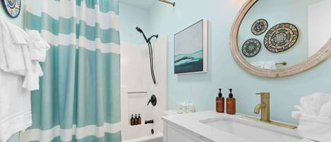 A bathroom with a shower, toilet, sink, and a towel rack.