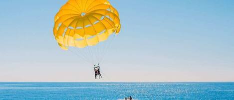 A parasailer over a calm sea with a clear sky.