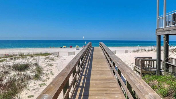 A wooden boardwalk leading to a beach with a clear view of the ocean.
