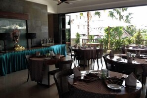 A restaurant with round tables, chairs, and a view of the outdoors. - Aria Exclusive Villas & Spa (Bali)