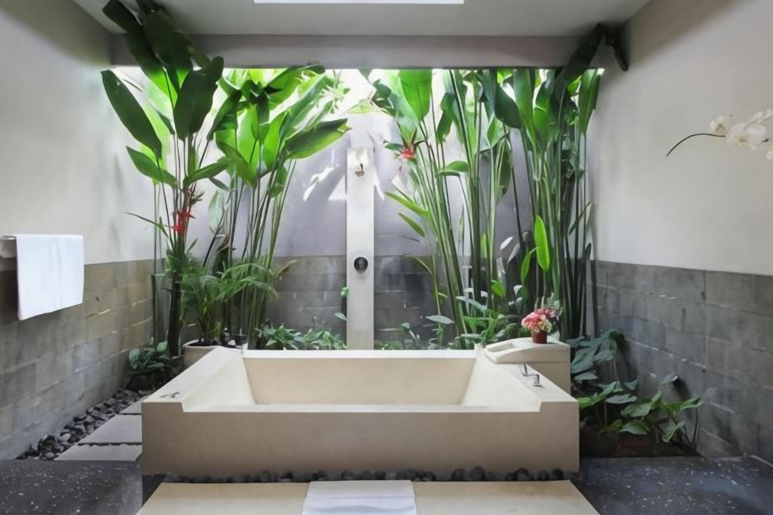 Zona de spa con bañera, plantas y un perchero para toallas.