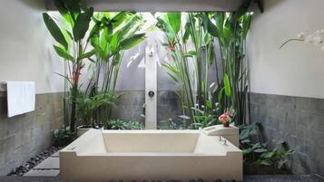Zona de spa con bañera, plantas y un perchero para toallas.