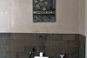 A bathroom with a tiled wall, a metal artwork, and a white toilet. - Aria Exclusive Villas & Spa (Bali)