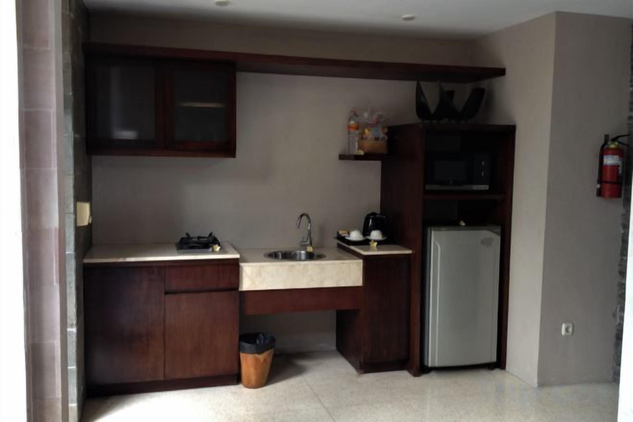 Cocina compacta con refrigerador, lavamanos y armarios.