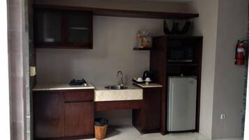 Cocina compacta con refrigerador, lavamanos y armarios.