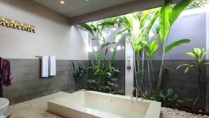A modern bathroom with a large bathtub, a shower, and a wall-mounted towel rack. - Aria Exclusive Villas & Spa (Bali)