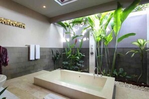 A modern bathroom with a large bathtub, a shower, and a wall-mounted towel rack. - Aria Exclusive Villas & Spa (Bali)