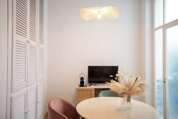 A room with a round table, a television on a wooden cabinet, a speaker, and a decorative vase with dried flowers. - Hostal Boutique La Malagueña Only Adults by Croma (Estepona)