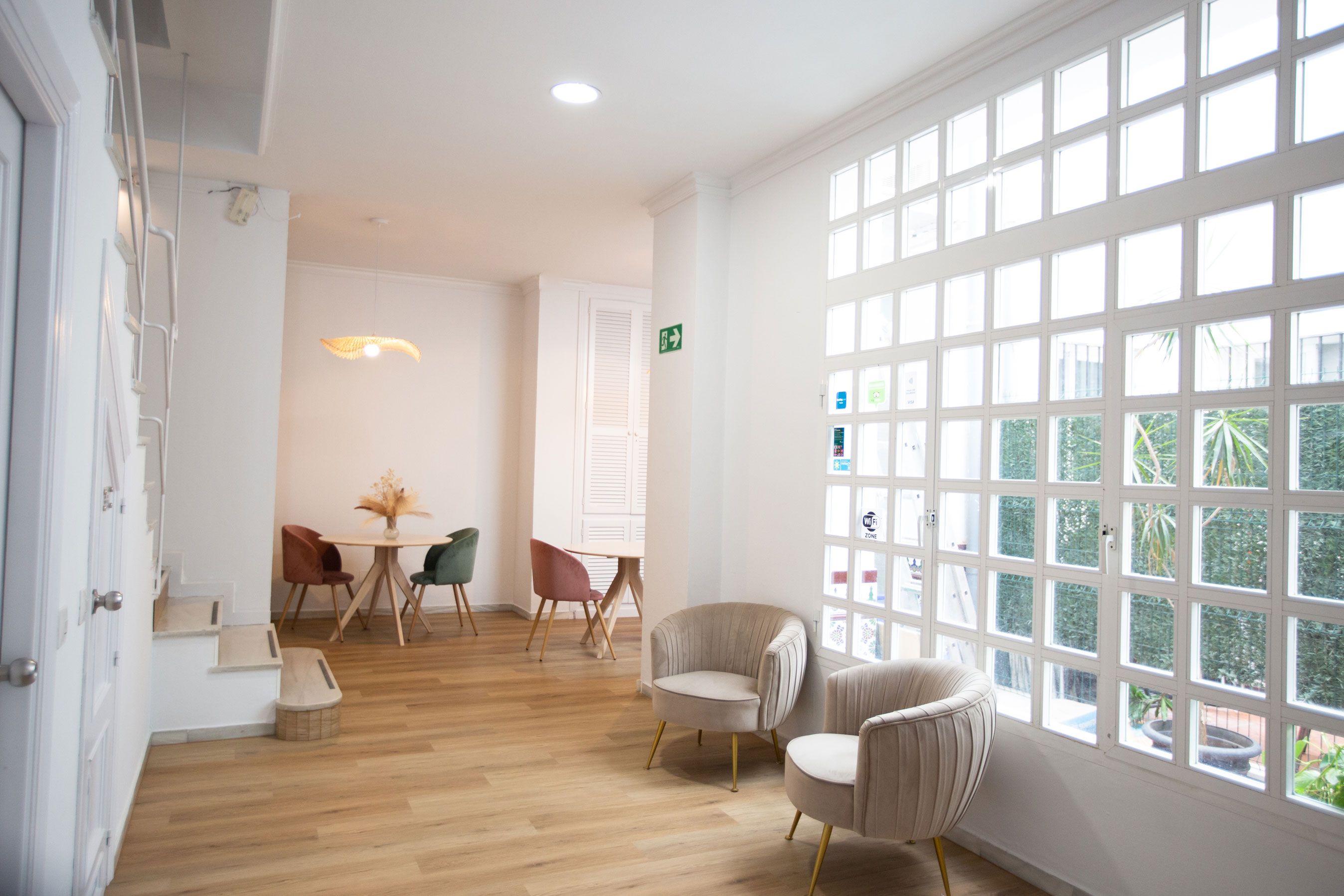 Una habitación luminosa con un gran ventanal, suelo de madera y una mesa con sillas.